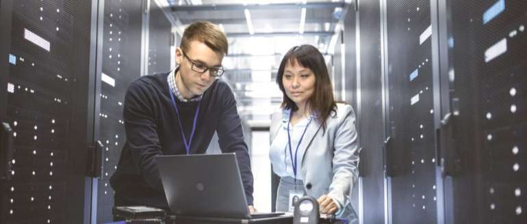 Man and woman working on laptop in data center